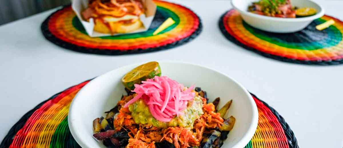 Descripción imagen: Tres platos con comida, servidos encima de manteles individuales artesanales. 